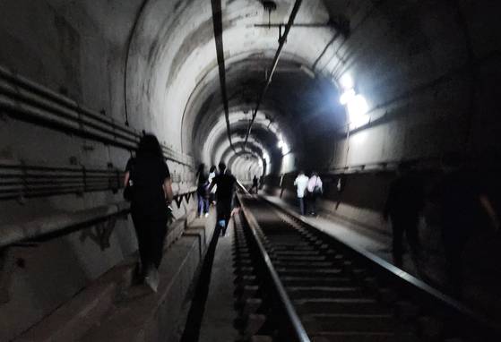 Passengers of Line No. 5 subway evacuate through a tunnel on the morning of May 31 after a fire broke out inside the compartment. [YONHAP]