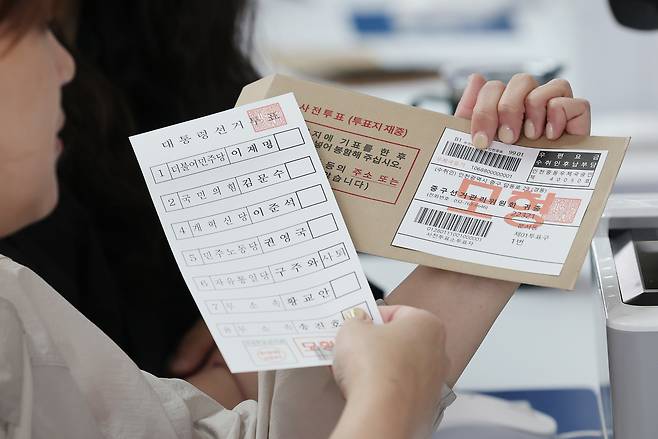 인천국제공항 1터미널에 설치된 제21대 대통령선거 사전투표소에서 관계자가 투표용지와 관외 사전투표자를 위한 회송용 봉투를 들어보이고 있다. [연합]