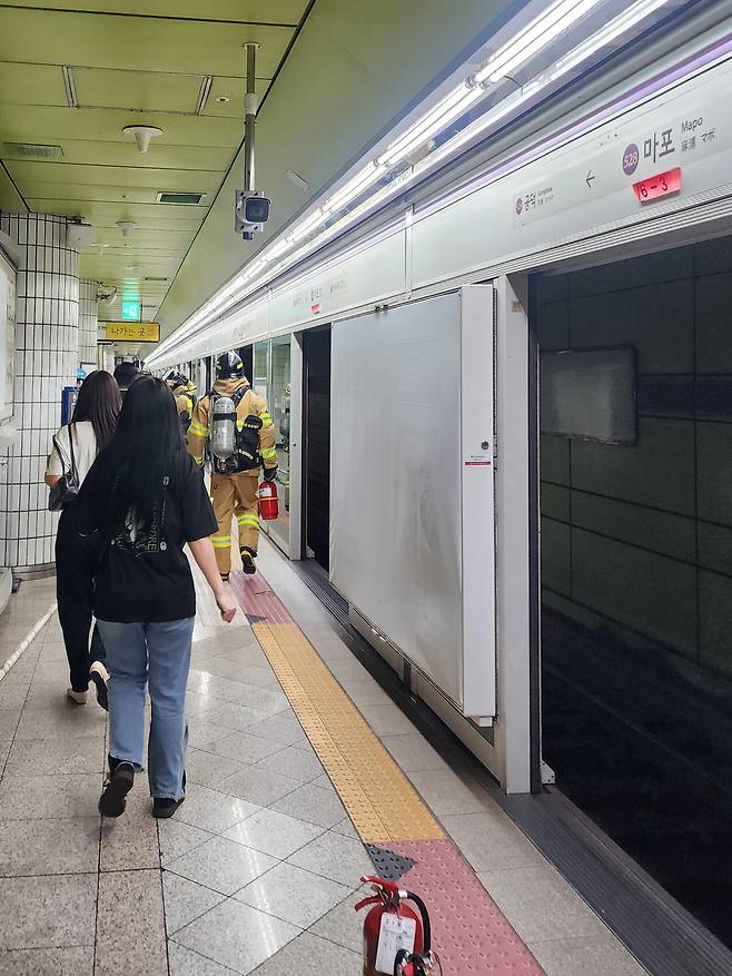 31일 오전 8시 45분쯤, 서울 지하철 5호선 마포역에서 열차 화재가 발생해 소방대원들이 승강장을 통해 현장으로 진입하고 있다. 바닥에는 진화에 사용된 소화기가 놓여 있다. 연합뉴스