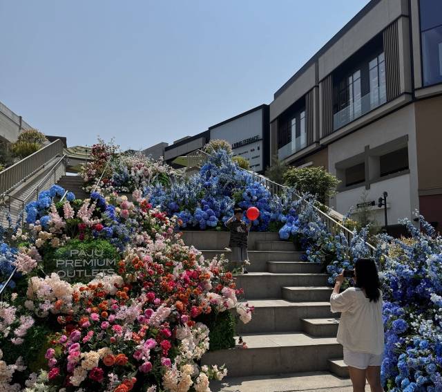 신세계사이먼 파주 프리미엄 아울렛 센트럴 스퀘어에 조성된 브리즈 블룸 가든(Breezy Bloom Garden)을 수 놓은 수국들을 배경으로 고객들이 사진을 촬영하고 있다. 신세계사이먼 제공