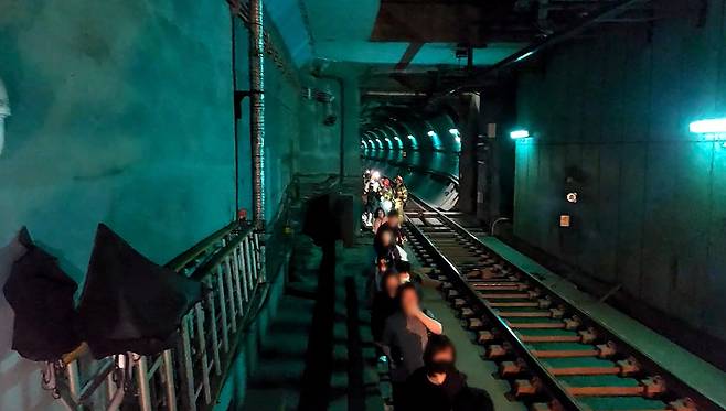 Passengers are being led toward safety by local rescue authorities, after an arsonist set a Seoul subway train on fire on Saturday morning. (Yonhap)