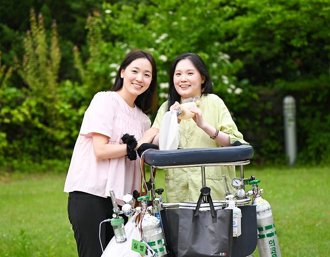 김온유(오른쪽) 작가가 최근 서울 강남구 한 종합병원 내 산책로에서 앰부(수동식 인공호흡기)를 잡은 채 동생 김주영씨와 함께 활짝 웃고 있다. 신석현 포토그래퍼