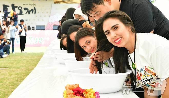 지난 1일 열린 자인단오제 '외국인 유학생 창포머리감기 시연'행사에 참여한 외국인 학생들이 창포물에 머리를 감는 체험을 하고 있다.(경산시 제공. 재판매 및 DB금지) 2025.6.2/뉴스1 ⓒ News1 정우용 기자