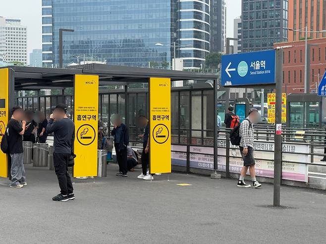 서울역광장이 금연 구역으로 지정된 가운데, 흡연자들이 2일 오전 흡연 부스에서 담배를 피우고 있다. 흡연 부스 밖에서 담배를 피우다 적발되면 과태료 10만원이 부과된다. 일부 흡연자들은 부스 입구 바깥에서 담배를 피워 단속원이 경고를 했다. /이호준 기자