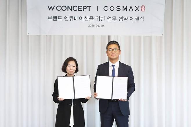 안지수 W컨셉 상품기획담당(왼쪽)과 최재우 코스맥스 국내마케팅본부 부문장(오른쪽)이 업무협약 체결 후 기념사진을 촬영하고 있다. W컨셉 제공