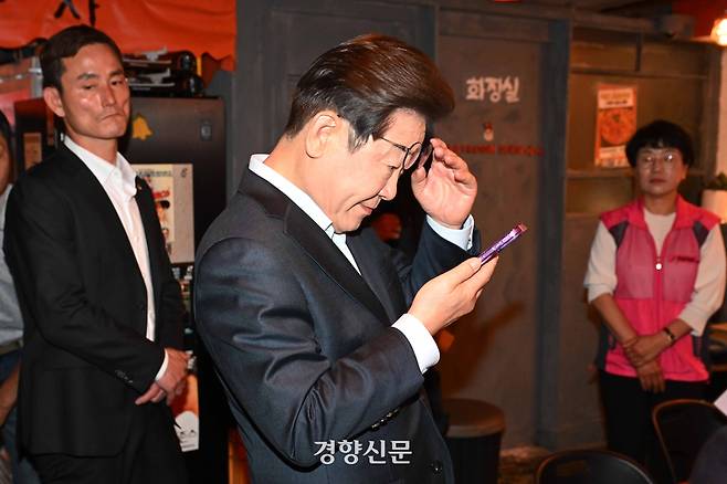 이재명 더불어민주당 대선 후보가 지난달 1일 서울 종로구의 한 음식점에서 열린 비전형 노동자 간담회 종료 후 당 관계자에게 전달받은 휴대전화를 확인하고 있다. 대법원 전원합의체는 이날 이 후보에게 무죄를 선고한 원심판결을 파기하고 사건을 서울고법으로 돌려보냈다. 조태형 기자