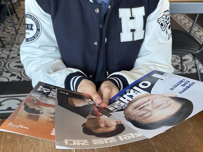 University student Lee June-seong, 25, looks at election pamphlets of the three major candidates — Lee Jae-myung of the Democratic Party of Korea, Kim Moon-soo of the People Power Party and Lee Jun-seok of the New Reform Party — during an interview with The Korea Herald at Hanyang University in Seongdong-gu, eastern Seoul, Tuesday. (Lee Jung-joo/The Korea Herald)
