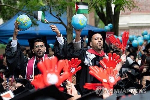 하버드 케네디스쿨 졸업생들 (케임브리지<미국 매사추세츠주> AFP=연합뉴스) 2025년 5월 29일 미국 매사추세츠주 케임브리지 소재 하버드대에서 열린 졸업식에서 이 대학 케네디 행정대학원 졸업생들이 지구본과 팔레스타인 국기를 들고 흔들고 있다. (Photo by Rick Friedman / AFP) 2025.6.2.
