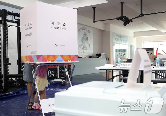 제21대 대통령 선거일인 3일 부산 수영구 레슬링넘버원 멀티짐에 마련된 남천제2동 제3투표소에서 유권자가 아이와 함께 투표를 하고 있다. 2025.6.3/뉴스1 ⓒ News1 윤일지 기자