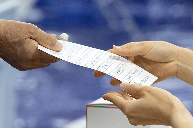 제21대 대통령 선거일인 3일 서울 영등포구 여의도 윤중중학교에 마련된 투표소를 찾은 시민이 투표용지를 받고 있다. /뉴스1