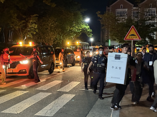 3일 오후 9시쯤 계명대학교 성서캠퍼스 체육관 앞 도로 위에 줄지어진 투표함 호송차량들 앞으로 투표사무원들이 투표함을 옮기고 있다. 구경모기자