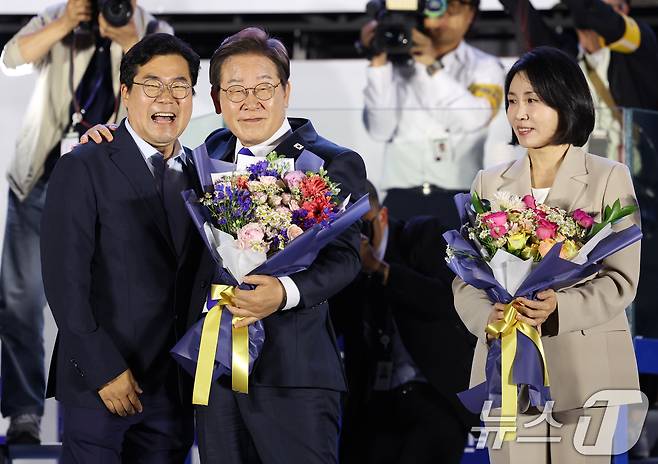당선이 확실시된 이재명 더불어민주당 대통령 후보가 김혜경 여사와 4일 오전 서울 여의도 국회 앞을 찾아 박찬대 상임총괄선대본부장으로부터 꽃다발을 받고 있다. (공동취재) 2025.6.4/뉴스1 ⓒ News1 안은나 기자
