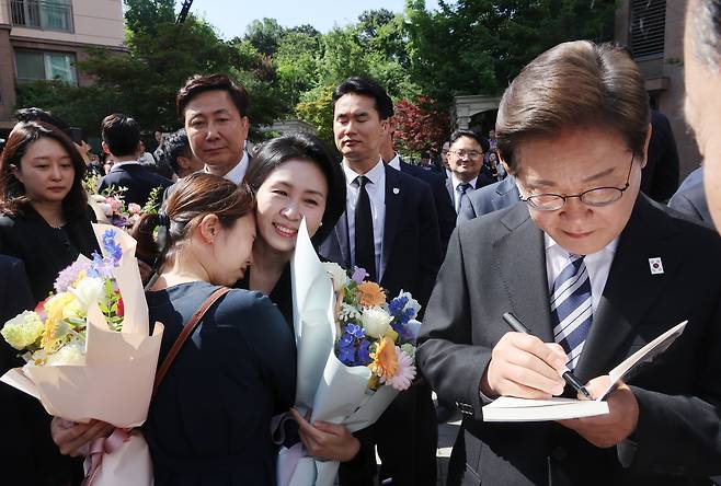 이재명 대통령이 4일 인천 계양구 사저를 출발하기 전 한 지지자가 준비한 자신의 자서전에 서명하고 있다. /연합뉴스