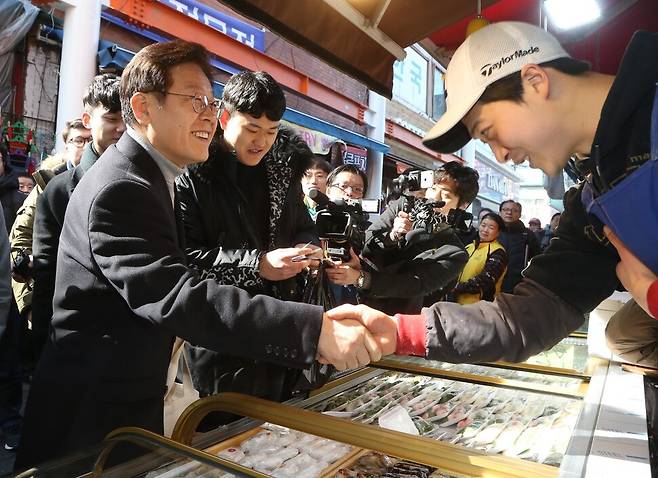 2017년 2월20일 이재명 당시 성남시장이2017년 2월20일 오전 성남시가 시행하고 있는 `청년배당\'을 직접 체험해보려고 경기 성남 상대원 재래시장을 방문해 청년에게 지급되는 삳품권으로 떡을 사고 있다. 한겨레 자료