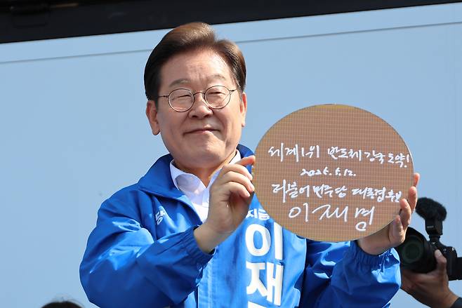 이재명 대통령이 지난달 12일 경기 화성시 동탄 센트럴파크 음악분수중앙광장 유세장에서 ‘세계1위 반도체 강국 도약!’이라고 쓴 반도체 웨이퍼를 들어 보이고 있다. [연합]