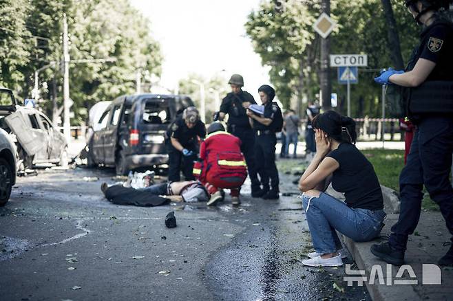 [수미=AP/뉴시스] 6월 3일 러시아의 공습을 받은 우크라이나 수미에서 구조대가 희생자 시신을 수습하는 동안 한 여성이 충격과 슬픔에 빠진 채 길 가에 앉아 있다. 러시아군의 공습으로 최소 3명이 숨지고 20명이 부상한 것으로 전해졌다. 2025.06.04.