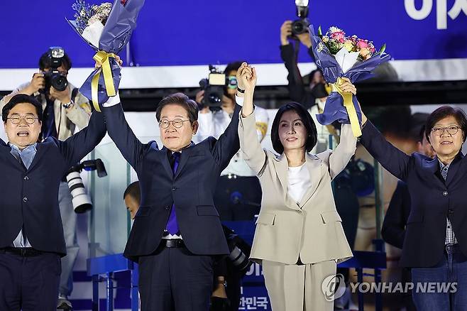 축하 꽃다발 받는 이재명 후보와 김혜경 여사 (서울=연합뉴스) 김주성 기자 = 제21대 대통령 당선이 확실시되는 더불어민주당 이재명 대선 후보와 부인 김혜경 여사가 4일 서울 여의도 국회 인근에서 당 주최로 열린 국민개표방송 행사에 참석해 박찬대 상임총괄선대위원장과 정은경 총괄선대위원장단으로부터 꽃다발을 받고서 시민들을 향해 두 팔을 들어 인사하고 있다. 2025.6.4 [공동취재] utzza@yna.co.kr