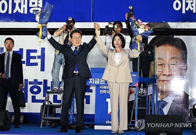 축하 꽃다발 받고 인사하는 이재명 후보와 김혜경 여사 (서울=연합뉴스) 김주성 기자 = 제21대 대통령 당선이 확실시되는 더불어민주당 이재명 대선 후보와 부인 김혜경 여사가 4일 서울 여의도 국회 인근에서 당 주최로 열린 국민개표방송 행사에 참석해 박찬대 상임총괄선대위원장과 정은경 총괄선대위원장단으로부터 꽃다발을 받고서 시민들을 향해 두 팔을 들어 인사하고 있다. 2025.6.4 [공동취재] utzza@yna.co.kr