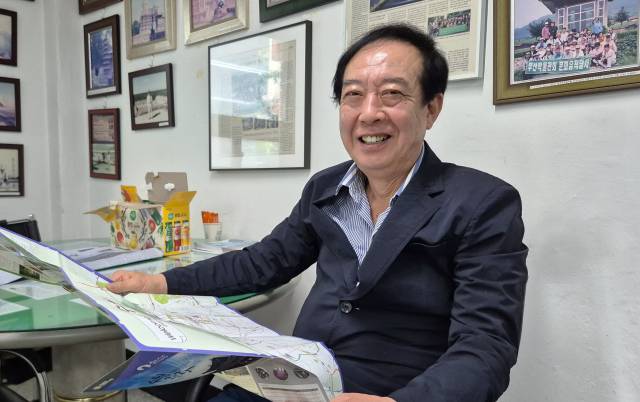 대륙항공여행사 장순복 대표가 지도를 펼치고 환하게 웃고 있다.