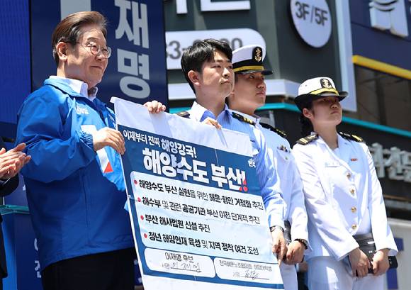 이재명 대통령(당시 대선 후보)이 지난달 14일 부산 부산진구 서면 젊음의 거리에서 열린 유세에서 권기흥 에이치라인해운해상직원노조 위원장과 해양수도 부산 협약서에 서명한 후 기념 촬영하고 있다. [사진=연합뉴스]