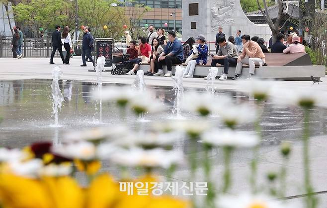 서울의 낮 최고기온이 25도를 기록하는 등 초여름 날씨를 보인 지난 4월 17일 오후 서울 종로구 광화문광장 분수대 앞에서 시민들이 겉옷을 벗어 들고 점심 산책을 하고 있다. [한주형기자]