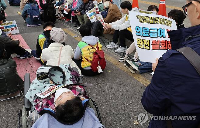 의료급여 정률제는... (서울=연합뉴스) 한상균 기자 = 기초법바로세우기공동행동, 무상의료운동본부, 보건의료단체연합 등 시민단체들이 29일 정부서울청사 인근에서 개최한 의료급여 정률제 철회 촉구 결의대회에 한 장애인이 참가하고 있다. 2024.10.29 xyz@yna.co.kr