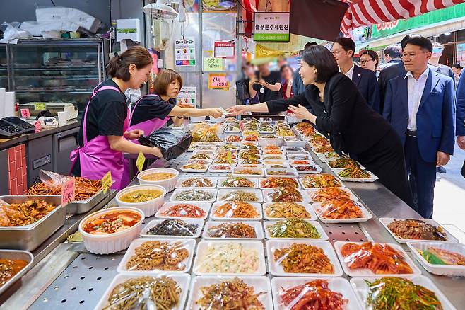▲ 김혜경 여사가 6일 서울 동작구 남성시장을 방문해 한 상점에서 식품을 구매하고 있다. /연합뉴스