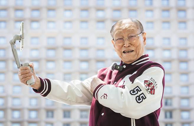 지난달 유튜브 채널을 개설한 이용만 전 재무부장관이 5일 오후 서울 중구 서울광장에서 모교 고려대 야구 점퍼를 입고 포즈를 취하고 있다. 왼쪽 팔에 ‘55학번’이란 문구가 적혀 있다. 사진 촬영이 이어지자 그는 “영정 사진이라도 찍으려는 거냐”라며 웃었다./김지호 기자