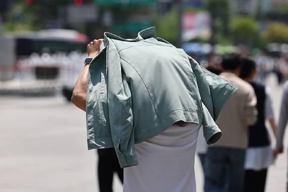 서울 한낮 기온이 26도까지 오르며 더운 날씨를 보인 지난달 14일 서울 종로구 광화문에서 한 시민이 겉옷으로 햇빛을 가리고 있다. [사진=연합뉴스]