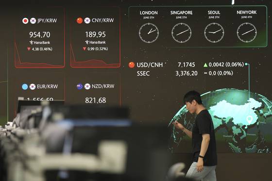 A dealer walks past near the screens showing foreign exchange rates at Hana Bank's dealing room in in central Seoul on June 5. [AP/YONHAP]