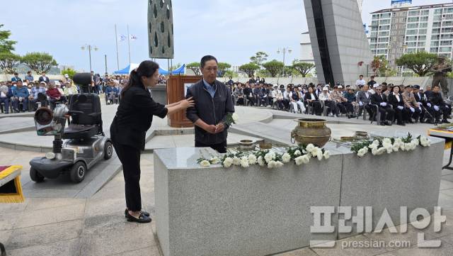 ▲보령시 궁촌동에 거주하는 김종면(우측 가운데)씨가 전동휠체어에서 내려 보령시청 공무원의 부축과 안내를 받으며 헌화하고 있다 ⓒ프레시안(이상원)