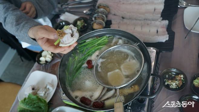 끓는 육수에 살짝 데쳐 양파 위에 올린 갯장어 샤부샤부. 억센 뼈가 먹는데 걸리지 않도록 잔칼질을 한 덕분에 육수에 넣으면 하얗게 핀 꽃처럼 변한다                    장흥｜김재범 기자 oldfield@donga.com