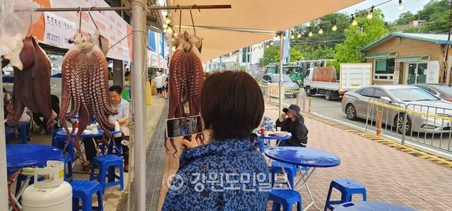▲ 저도어장에서 잡은 대문어를 숙회로 쪄 내건 모습을 관광객들이 영상과 사진으로 담고 있다.