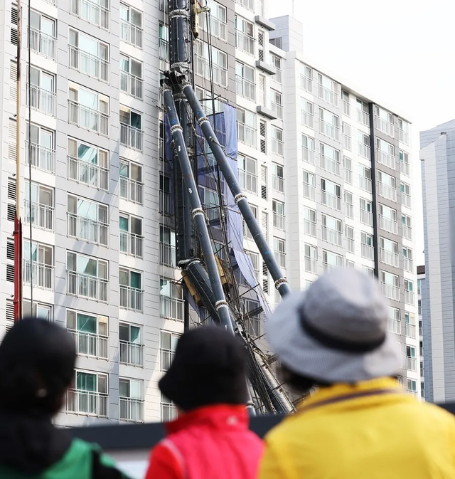 5일 경기 동탄 아파트 건물 벽면을 덮친 천공기를 바라보고 있는 시민들. 연합뉴스