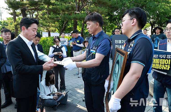 [서울=뉴시스] 고범준 기자 = 강훈식 대통령 비서실장이 6일 서울 용산 전쟁기념관 앞에서 태안화력발전소 사고 희생자 고(故) 김충현 씨와 관련해 엄길용 공공운수노조 위원장, 유족, 사고 대책위 관계자로부터 요구안 서한을 직접 받고 있다. (대통령실통신사진기자단) 2025.06.06. bjko@newsis.com