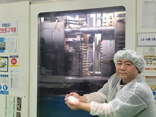 5일 제주삼다수 먹는샘물 생산라인에서 김준영 제주개발공사 상품개발팀 대리가 재생페트칩이 사출성형기에 투입돼 프리폼이 생산되는 과정을 시연하고 있다. 프리폼은 추후 페트 공병으로 제조돼 물을 충진하면 최종 제품이 생산된다. 사진 출처 : 환경부 기자단