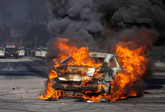 7일(현지시간) 미국 캘리포니아주 로스앤젤레스 남부 시외의 콤프턴에서 연방 이민당국의 이민 체포 작전에 대항하는 시위대의 방화로 차량이 불타고 있다.로이터=연합뉴스