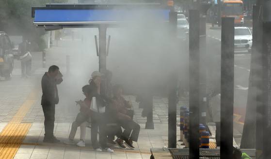 무더운 초여름 날씨를 보인 8일 부산 동구 부산진역 부근 횡단보도 앞에 설치된 그늘막 아래서 시민과들이 쿨링포그를 맞으며 더위를 식히고 있다. 송봉근 기자