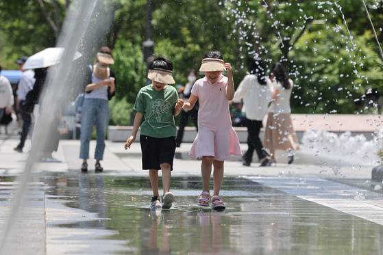 Children play at a fountain in Gwanghwamun, central Seoul, on June 5. [YONHAP]