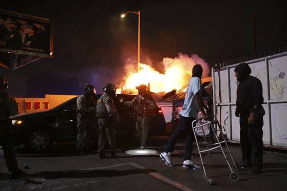 A man looks back at a fire after law enforcement helped him out of a car during a protest in Compton, Calif., Saturday, June 7, 2025, after federal immigration authorities conducted operations. [AP/YONHAP]