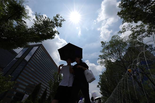 초여름 날씨를 보이는 8일 서울 광화문광장에서 시민들이 양산을 쓴 채 걸어가고 있는 모습. [연합]