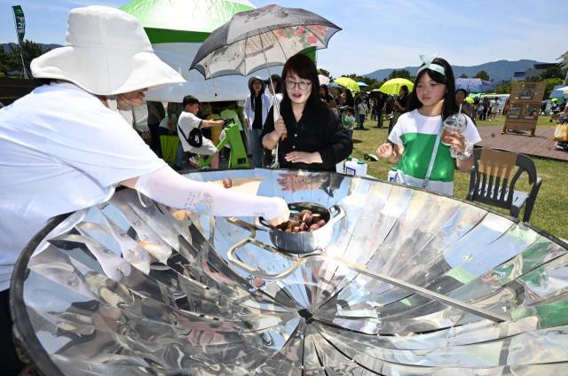 지난 7일 창원용지문화공원에서 열린 제17회 창원그린엑스포에서 참가자들이 태양광을 이용해 고구마를 굽는 모습을 살펴보고 있다./성승건 기자/