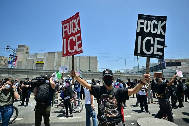 8일(현지시간) 캘리포니아주 로스앤젤레스 다운타운 연방 구금센터 인근에서 주방위군, 연방 경찰과 대치하는 시위대가 팻말을 들고 있다.(사진=AFP)
