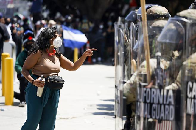 8일(현지 시각) 미국 캘리포니아주 로스앤젤레스 연방청사 밖에서 한 여성 시위자가  청사경비를 서고 있는 캘리포니아 주방위군 대원들에게 항의하고 있다. /EPA 연합뉴스