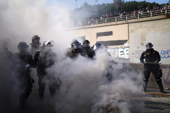 8일(현지시간) 미국 캘리포니아 로스앤젤레스 시내 메트로폴리탄 구치소 인근 101번 고속도로에서 연기 너머로 경찰들의 모습이 보이고 있다. AP연합뉴스