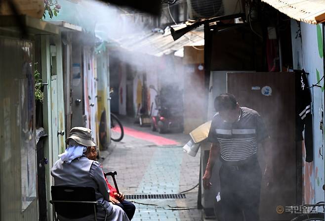 한낮 최고 기온이 30도 안팎까지 오른 9일 서울 영등포구 쪽방촌에서 주민들이 설치된 쿨링포그를 맞으며 더위를 식히고 있다