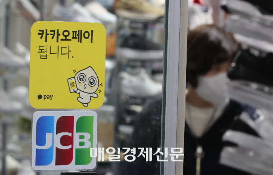 한 시민이 서울 명동 거리에 위치한 카카오페이 가맹점에서 물품을 구입하고 있다. [사진 = 매일경제]
