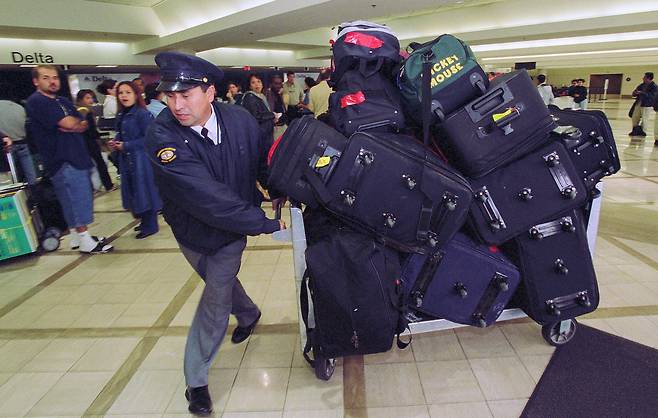 미국 로스앤젤레스 국제공항에서 한 직원이 승객들의 위탁 수하물들을 분주히 옮기고 있다. [게티이미지]