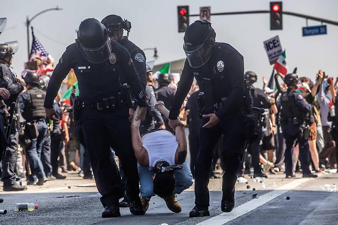 미국 캘리포니아주 로스앤젤레스에서 8일(현지시간) 이민 단속 반대 시위가 3일째 격화하는 가운데 경찰들이 한 시위 가담자를 체포하고 있다. [AFP]