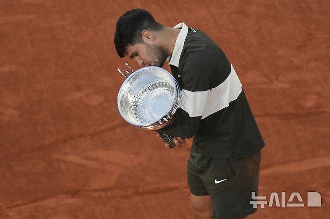 [파리=AP/뉴시스] 카를로스 알카라스(2위·스페인)가 8일(현지 시간) 프랑스 파리 롤랑가로스에서 열린 프랑스오픈 남자 단식 정상에 올라 트로피를 들고 입 맞추고 있다. 알카라스는 결승전에서 얀니크 신네르(1위·이탈리아)와 5시간 29분 대접전 끝에 3-2(4-6 6-7 6-4 7-6 7-6) 역전승을 거두고 대회 2연패를 달성했다. 2025.06.09.